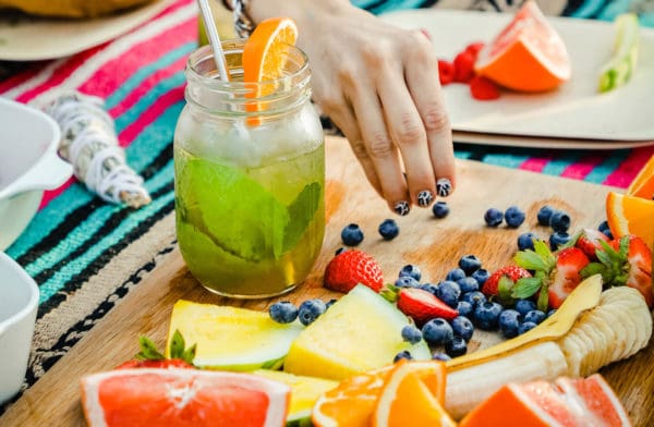 Fruit infused water with a variety of fruit on cutting board outside.