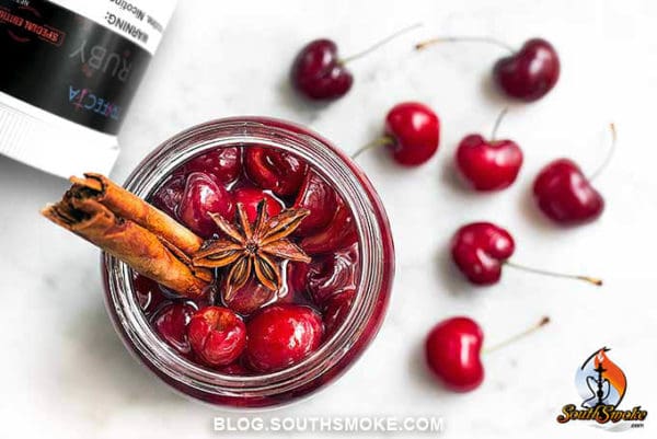 Cherries and cinnamon in glass jar with trifecta tobacco dark blend ruby on white table