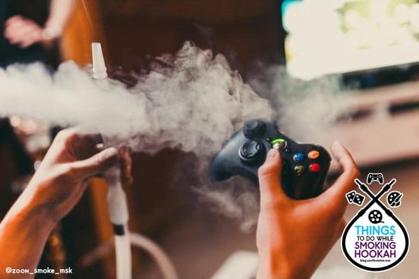 hands holding hookah hose and video game controller with smoke