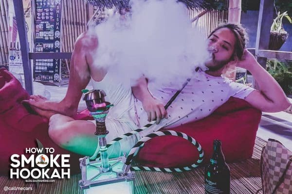 Man laying down smoking hookah.