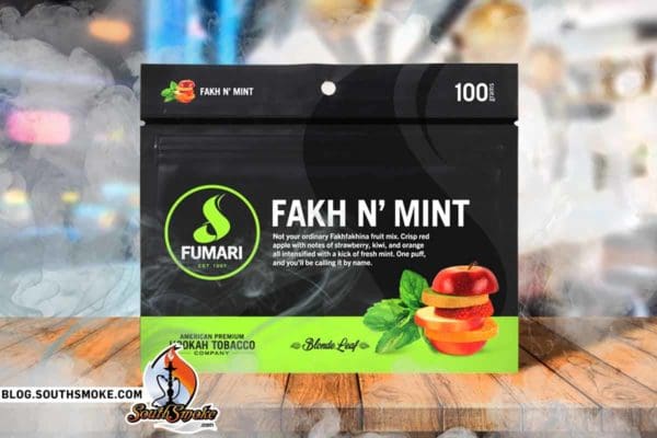 Fumari's Fakh N' Mint on a wooden table with smoke surrounding the 100g pouch in a lit hookah bar