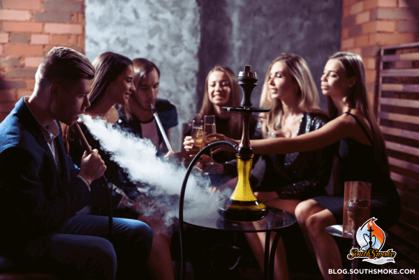 group of men and women sitting around hookah smoking and drinking champagne